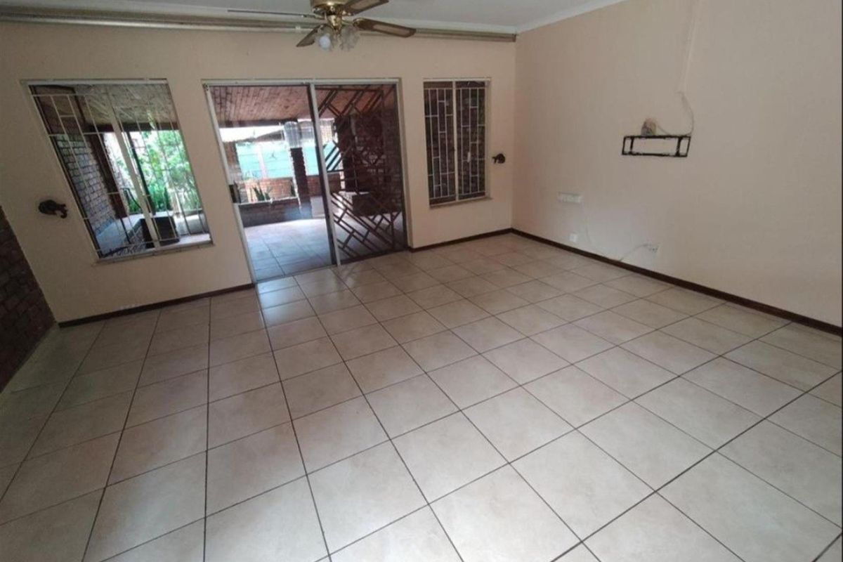 Spacious living area featuring neutral floor tiles, a ceiling fan, and sliding glass doors providing direct access to the outdoor patio.