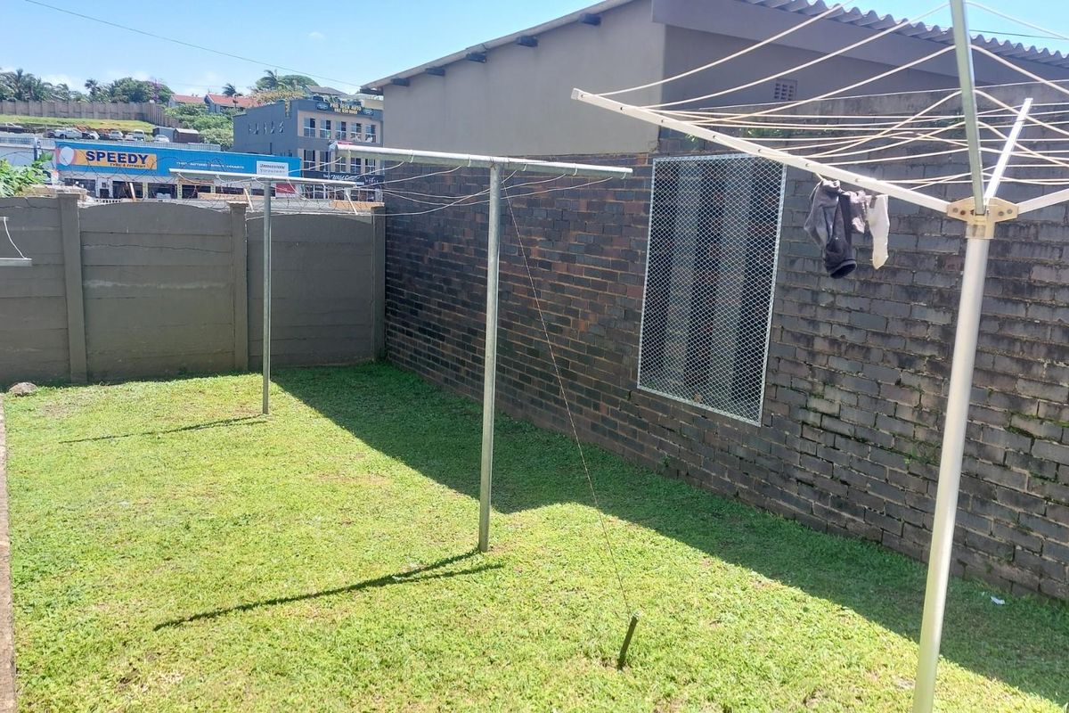A private rear garden area featuring a lawn, brick boundary walls, and fixed metal washing lines.
