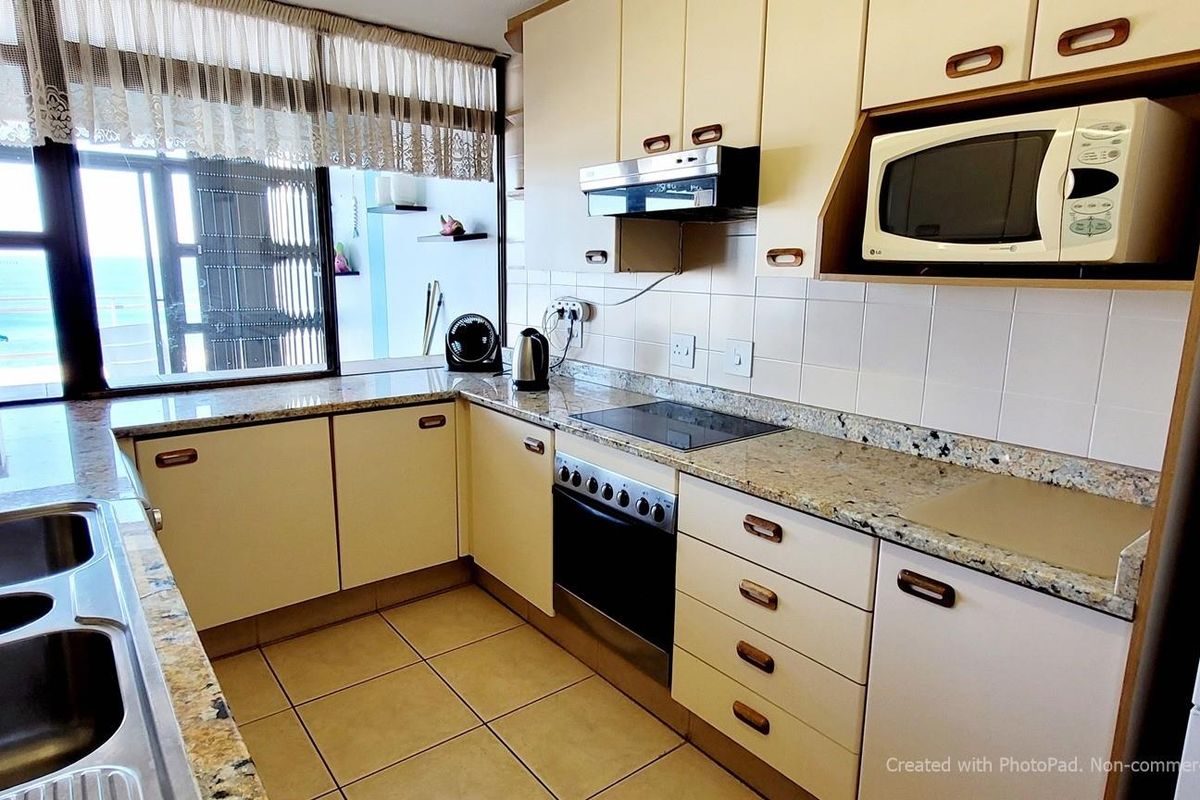 A functional kitchen featuring granite countertops, tiled flooring, built-in cabinetry, and an integrated oven with a hob.