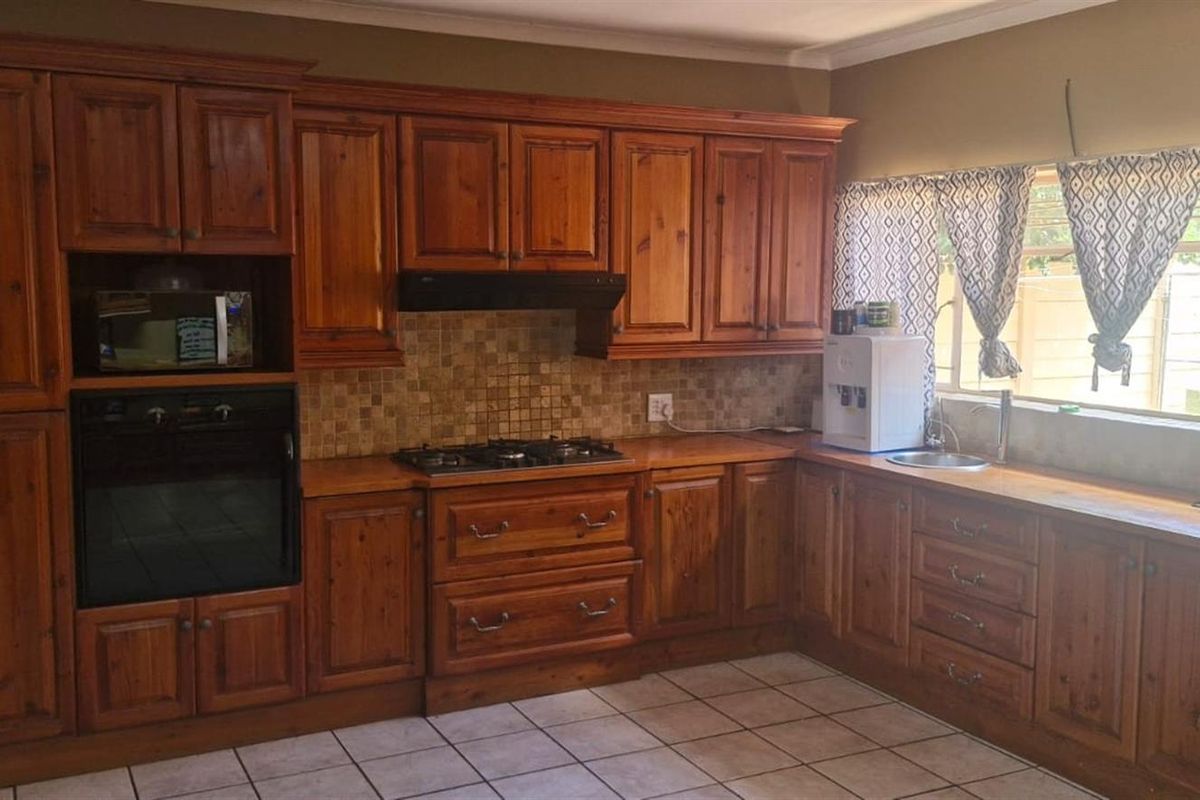 A functional kitchen featuring traditional wooden cabinetry, a built-in oven, gas hob, and tiled backsplash with ample counter space.