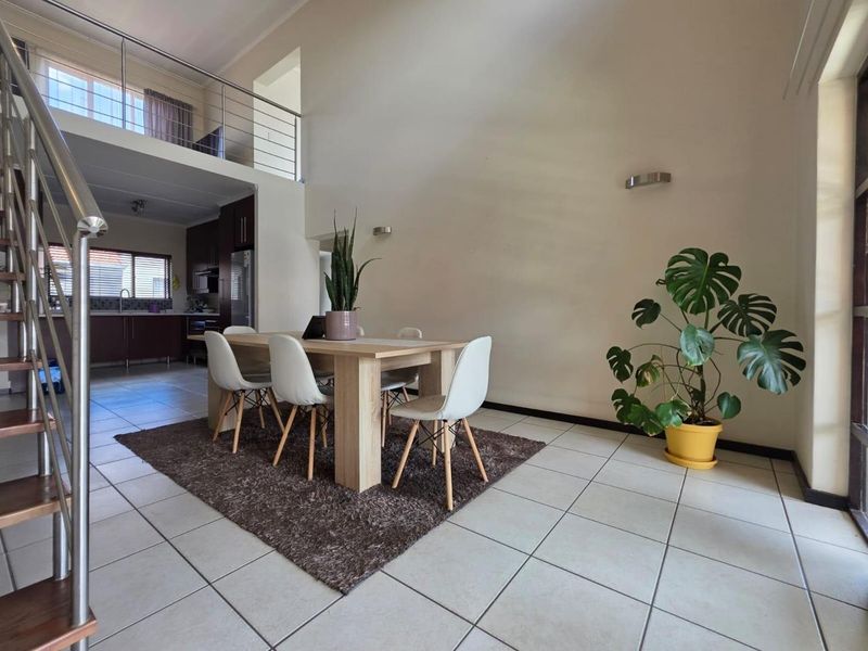 Spacious open-plan living and dining area featuring high ceilings, tiled flooring, and a mezzanine level overlooking the ground floor space.