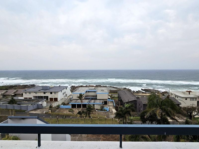 An elevated coastal view overlooking the ocean and surrounding residential neighborhood from a balcony.