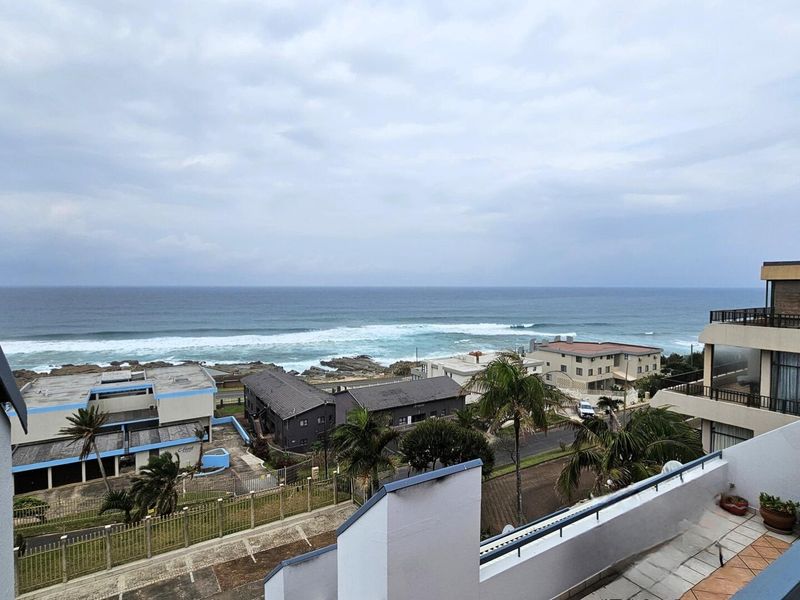 Elevated coastal view overlooking the ocean, surrounding residential properties, and local streetscape from a private balcony.