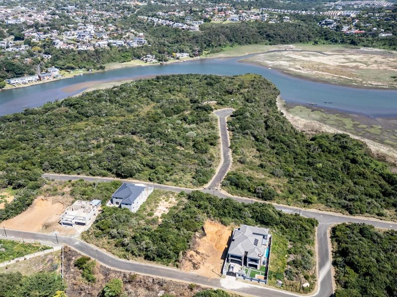 Aerial view of a residential estate development featuring vacant plots, paved roads, and scenic estuary frontage in a natural landscape setting.
