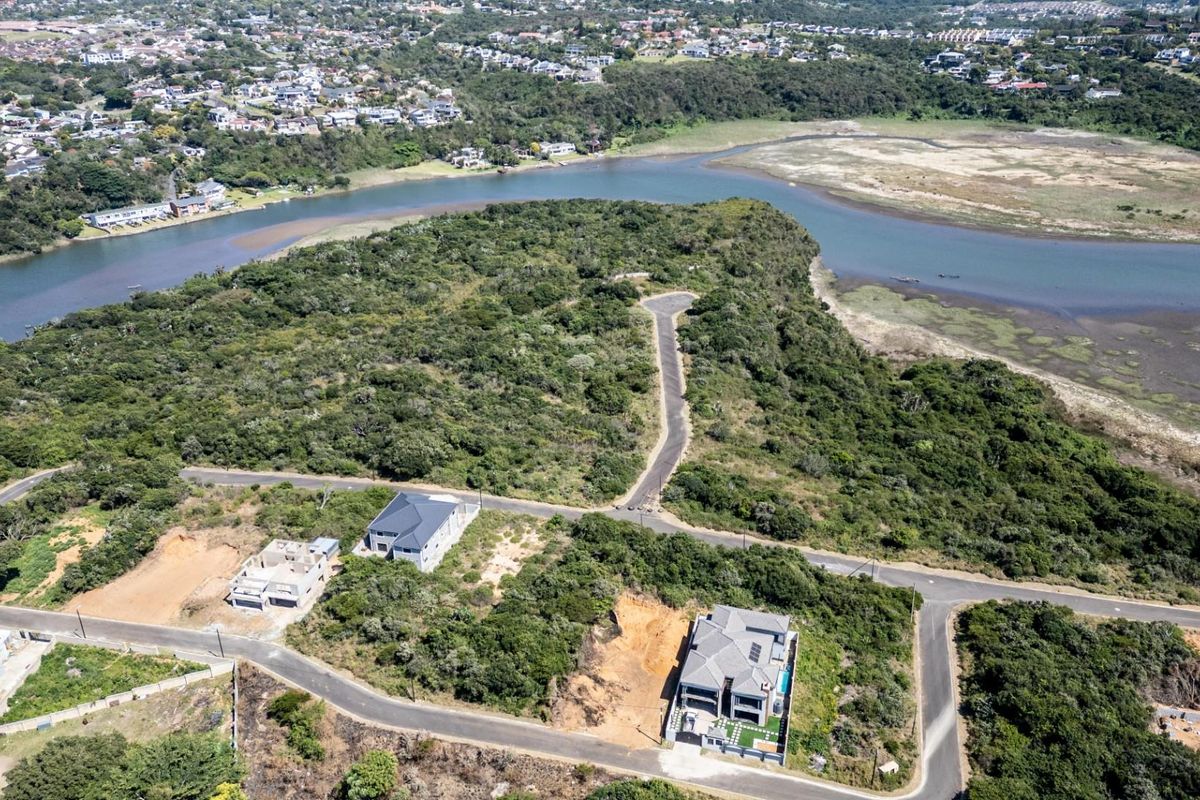 Aerial view of a residential estate development featuring vacant plots, paved roads, and scenic estuary frontage in a natural landscape setting.