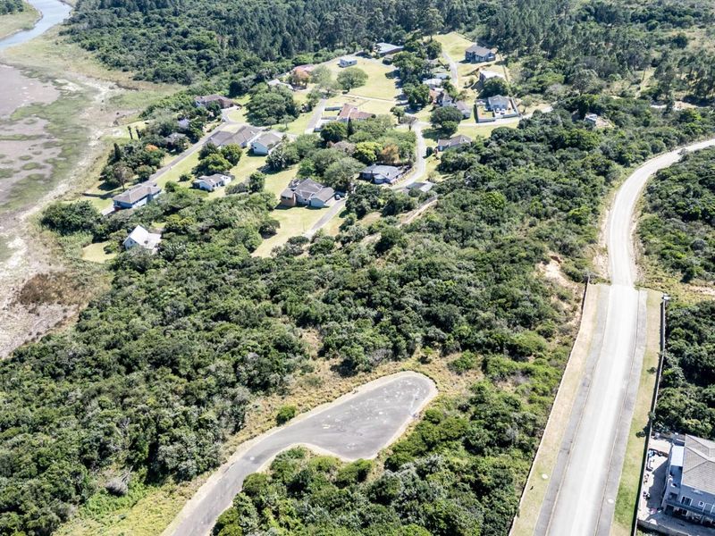 Aerial view of a vacant residential plot featuring natural coastal vegetation, road access, and proximity to the estuary.