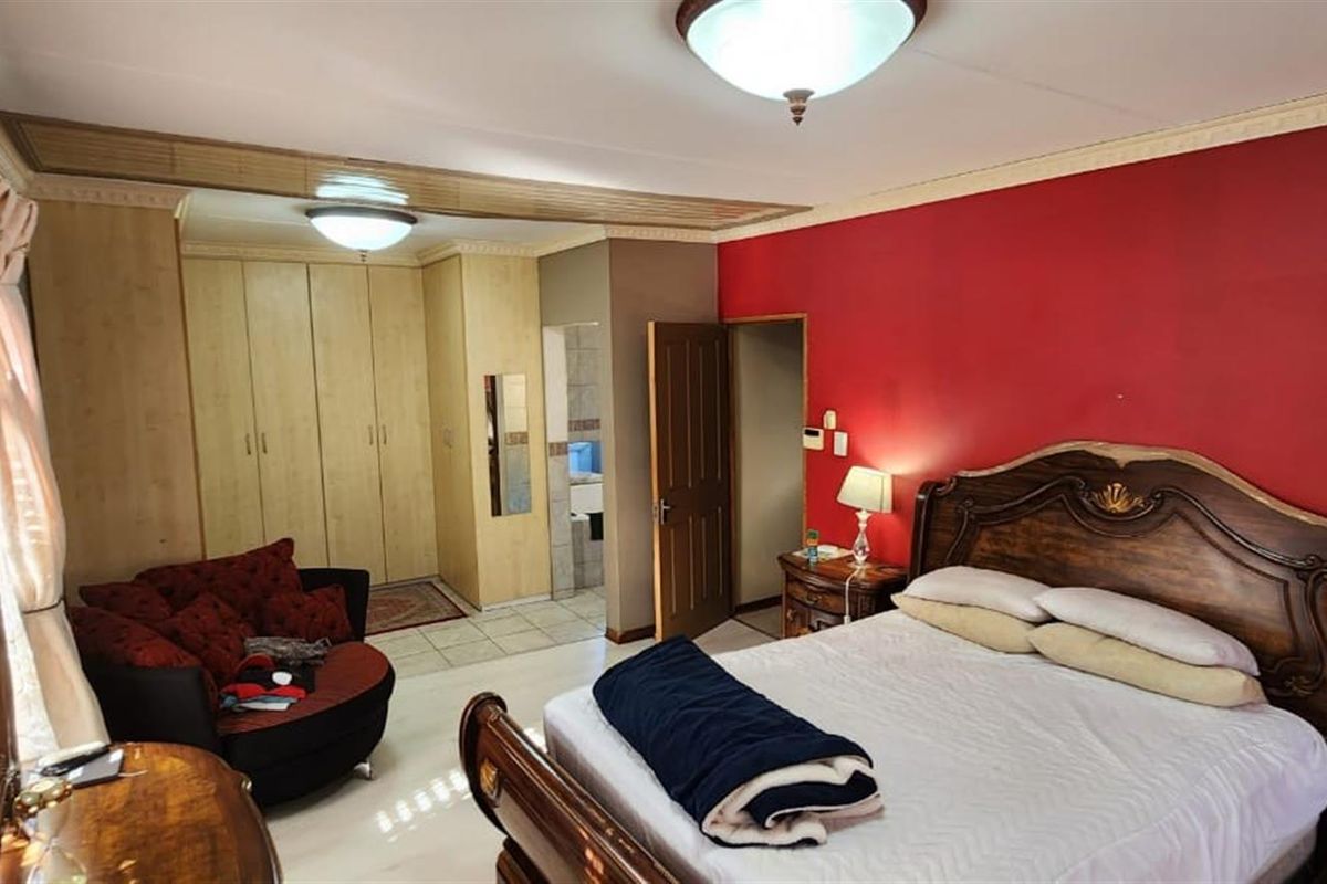 Spacious bedroom featuring built-in wooden cabinetry, tiled flooring, and an en-suite bathroom access point.