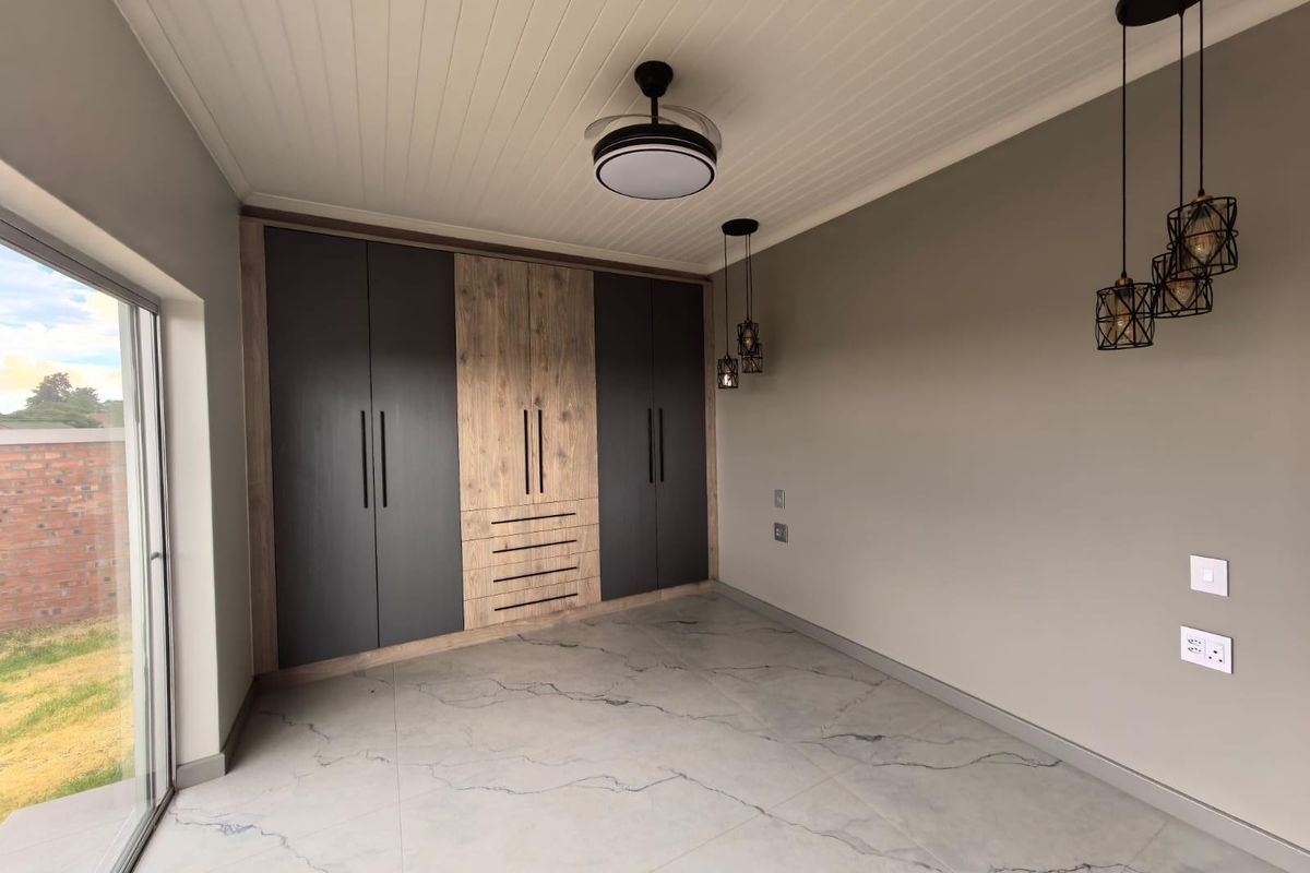Modern bedroom featuring built-in cabinetry with a mix of dark and wood-grain finishes, tiled flooring, and contemporary pendant lighting.