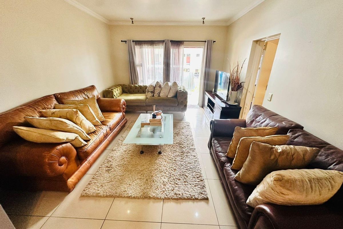 A spacious living room featuring tiled flooring, recessed ceiling lighting, and a sliding glass door providing access to the exterior.