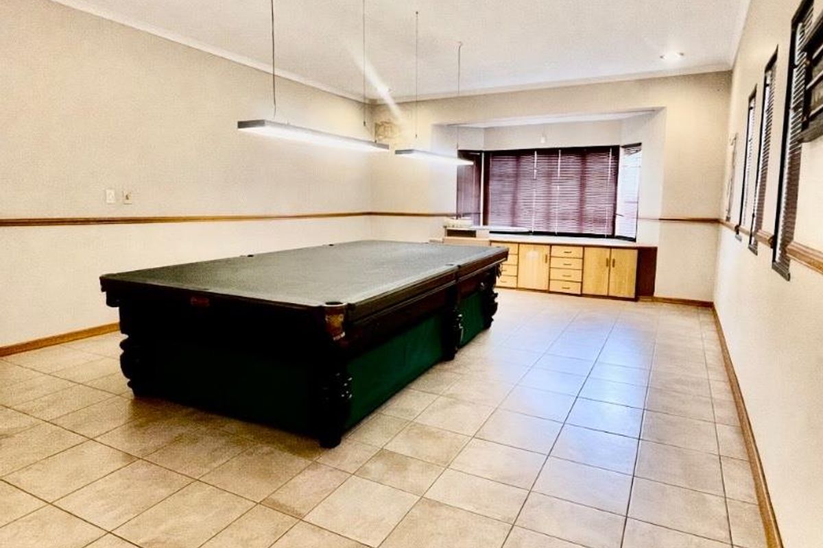 Spacious recreation room featuring tiled flooring, built-in cabinetry under a bay window, and dedicated overhead lighting fixtures.