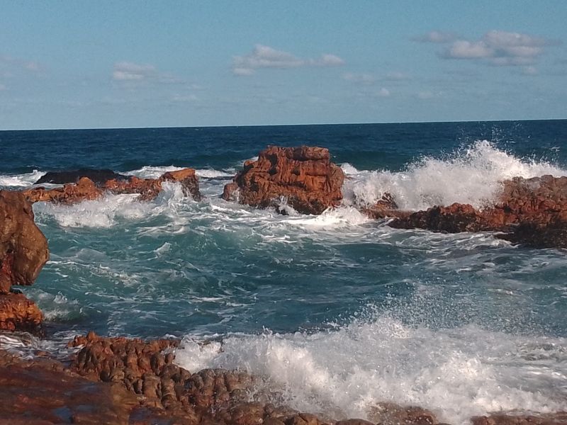 A scenic view of the ocean waves crashing against natural rock formations along the coastline.