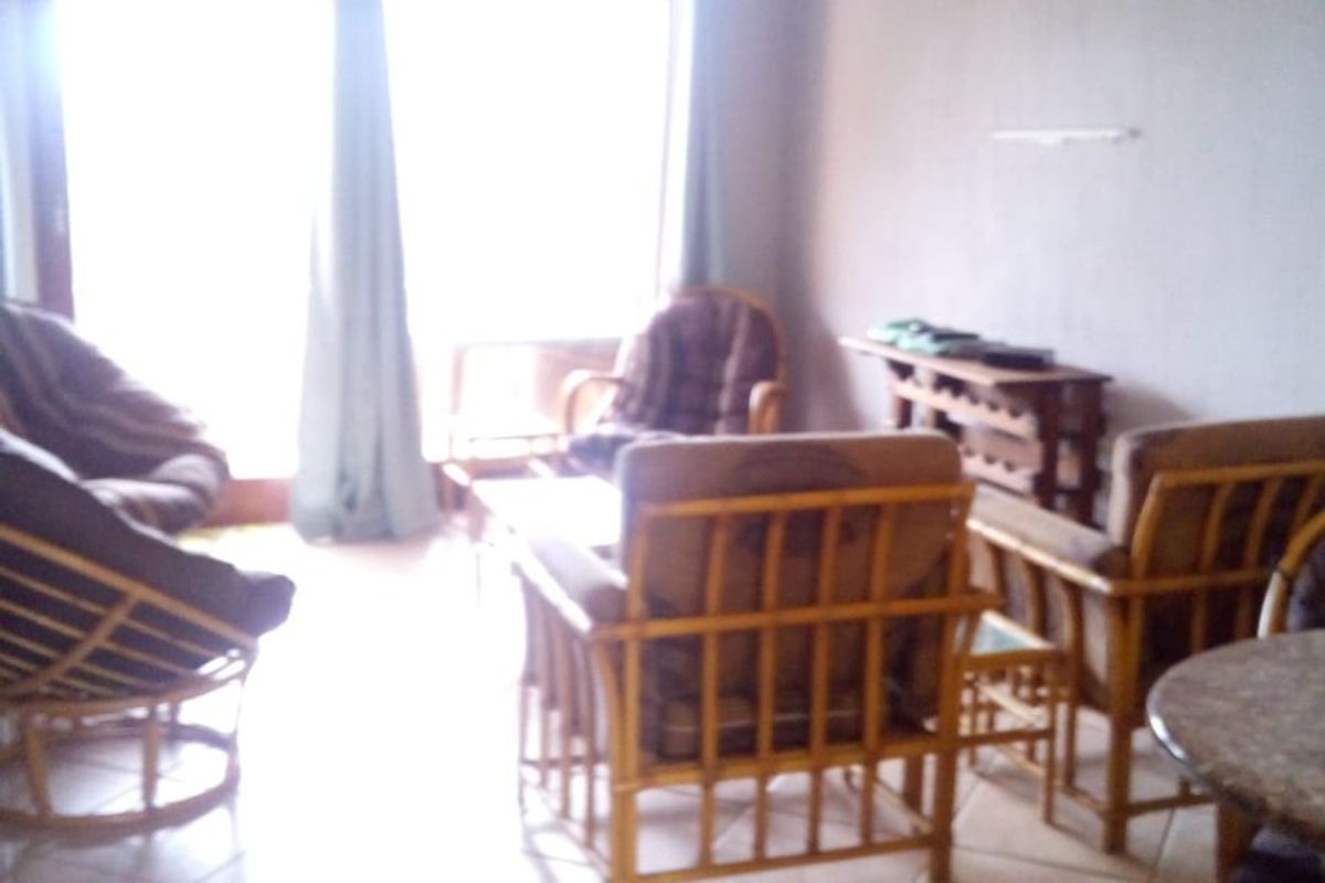 A living room area featuring tiled flooring and a large sliding glass door providing natural light.
