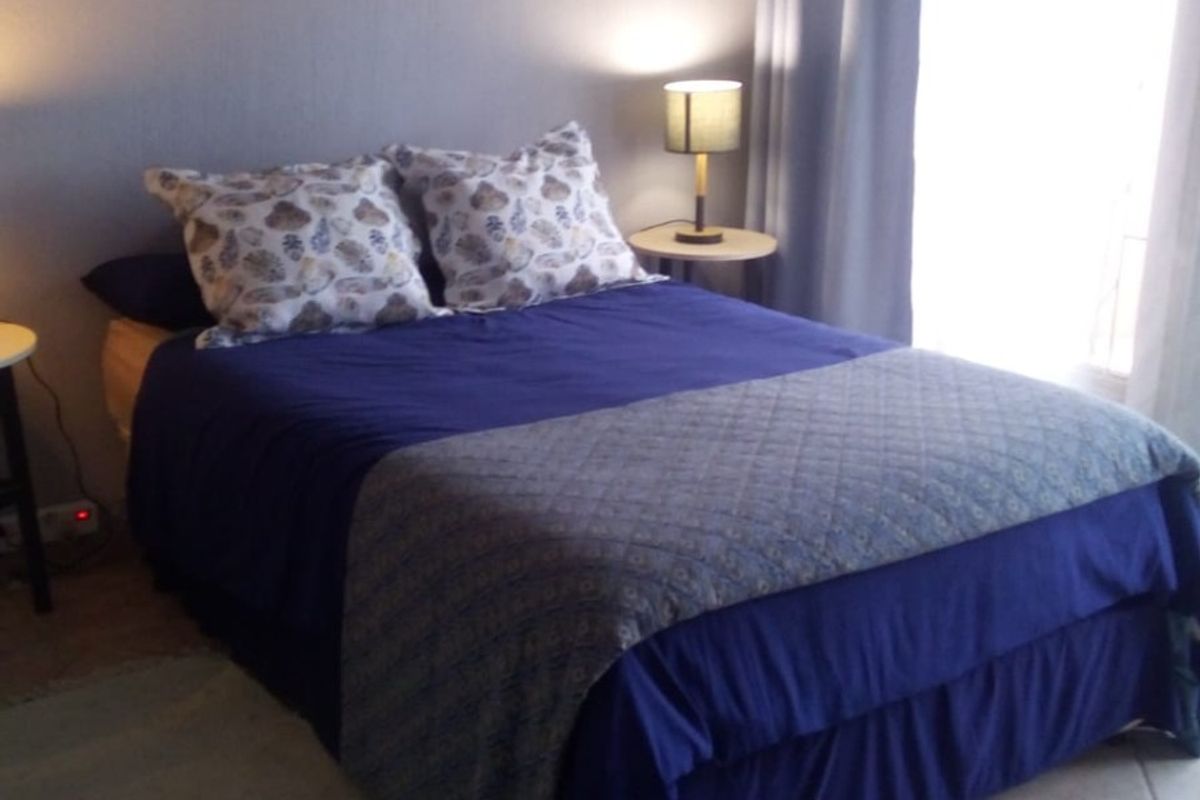 A bedroom featuring tiled flooring and natural light from a window with curtain tracks.