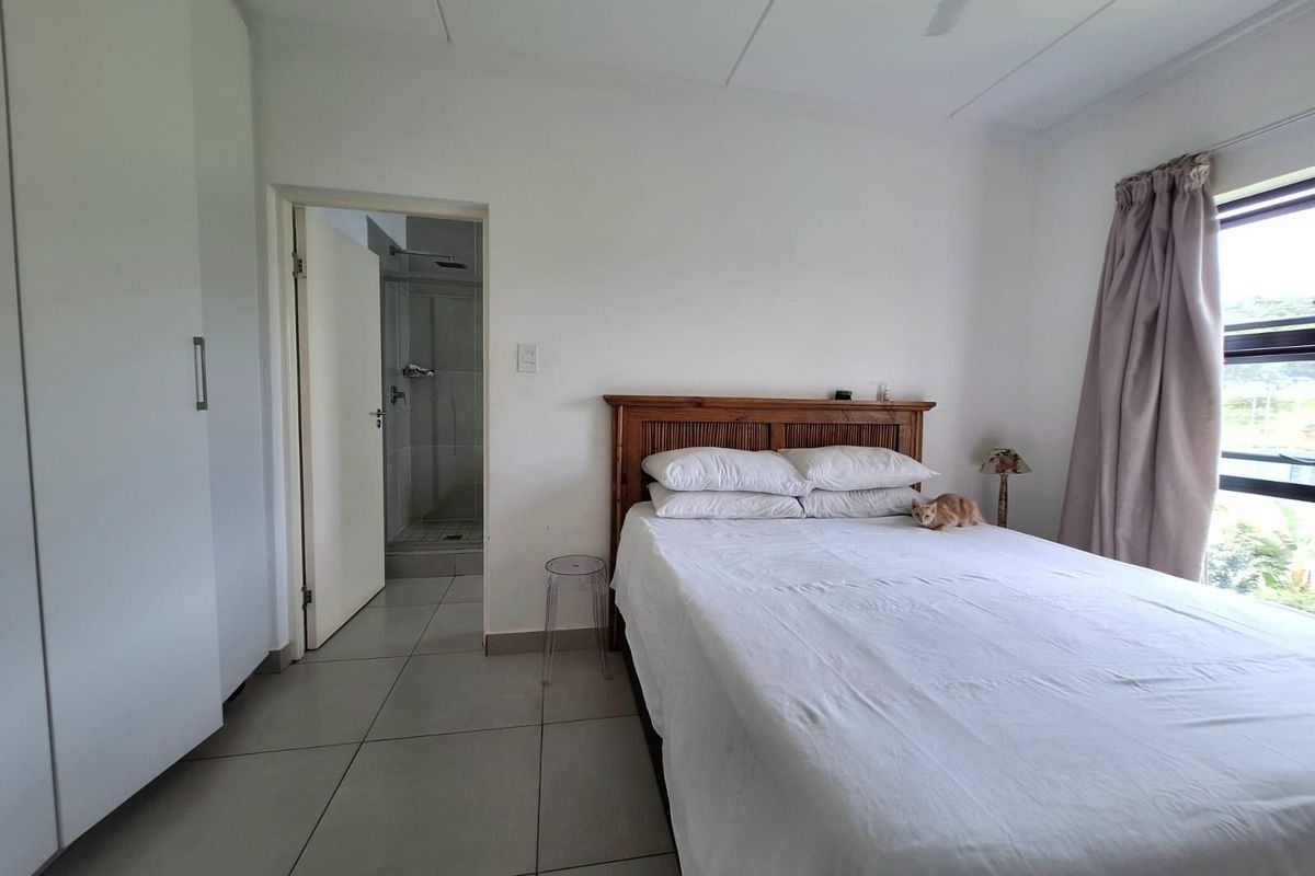 A bedroom featuring built-in cupboards, tiled flooring, and an en-suite bathroom with a shower.