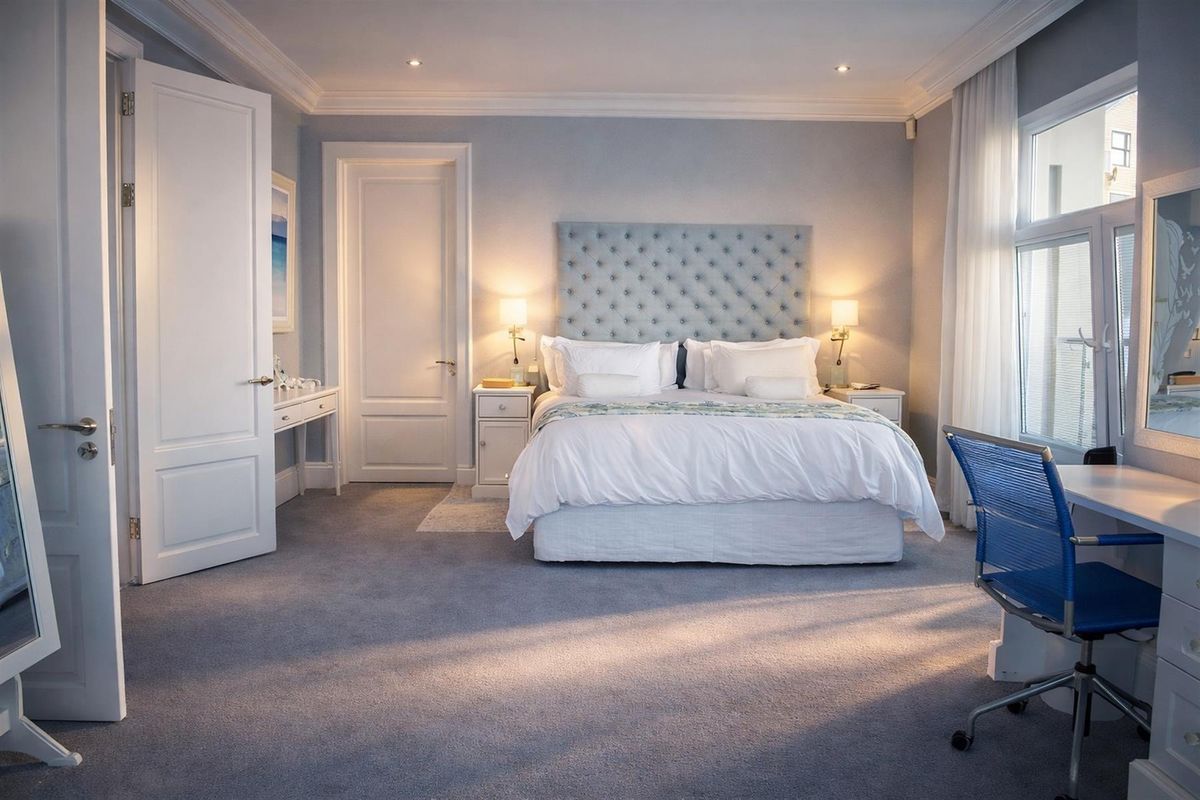 A well-appointed bedroom featuring crown molding, recessed lighting, and neutral carpeting, offering a clean and comfortable living space.