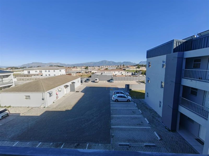 Elevated view overlooking the apartment complex parking area and surrounding neighborhood with mountain views in the distance.