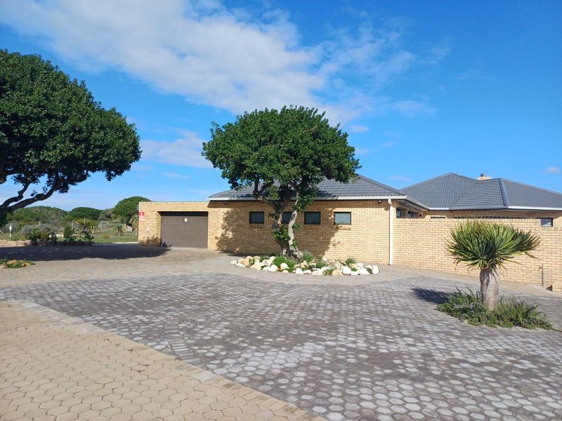 A well-maintained single-story brick house featuring a paved driveway, integrated garage, and landscaped front garden area.