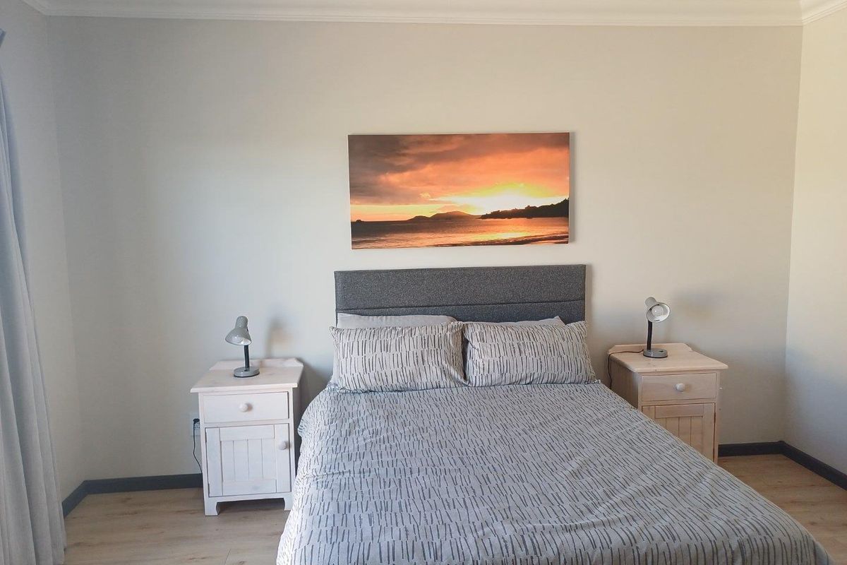 A well-maintained bedroom featuring light wood-look flooring, neutral wall tones, and crown molding.