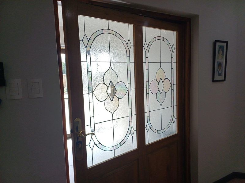 A solid timber door featuring decorative leaded glass panels, providing a classic aesthetic and natural light entry.