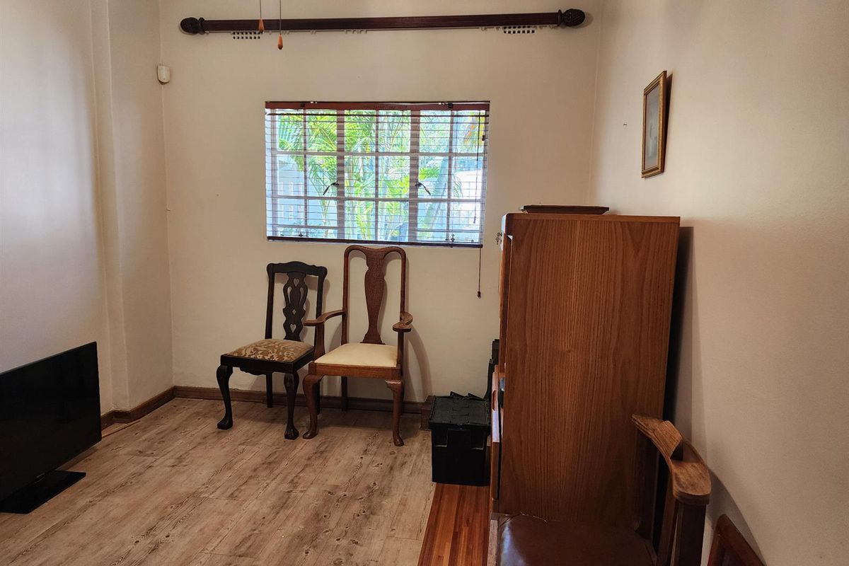 A bedroom featuring wood-look laminate flooring, a window with fitted blinds, and a curtain rod.