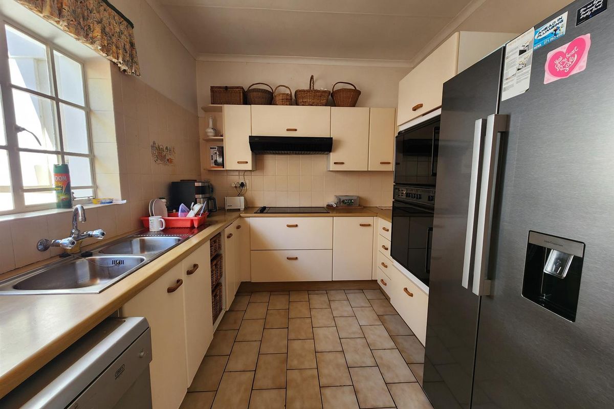 A functional kitchen featuring built-in cabinetry, a double sink, integrated oven, and tiled flooring, offering a practical layout for daily meal preparation.