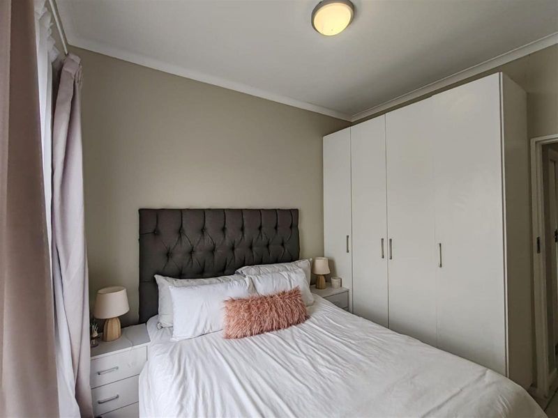 A well-maintained bedroom featuring built-in floor-to-ceiling wardrobes and neutral wall finishes.