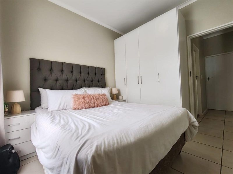A well-maintained bedroom featuring built-in floor-to-ceiling wardrobes and neutral tiled flooring, offering a clean and functional living space.