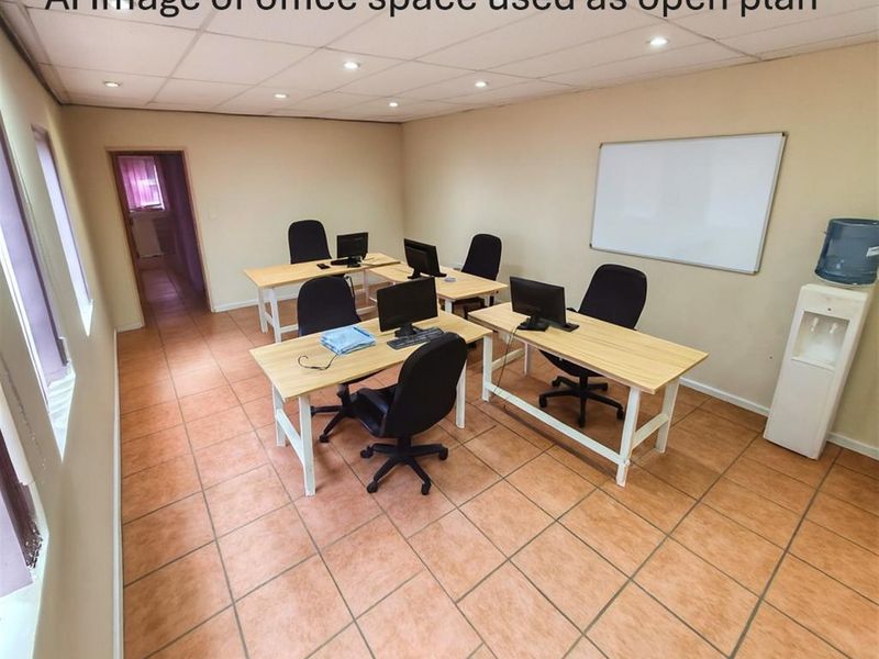 Open plan office space featuring tiled flooring, recessed ceiling lighting, and a wall-mounted whiteboard, suitable for a collaborative work environment.