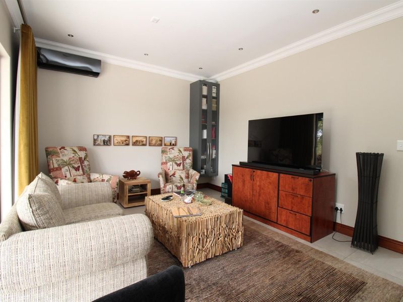 A comfortable living room featuring tiled flooring, recessed ceiling lighting, crown molding, and a wall-mounted air conditioning unit.