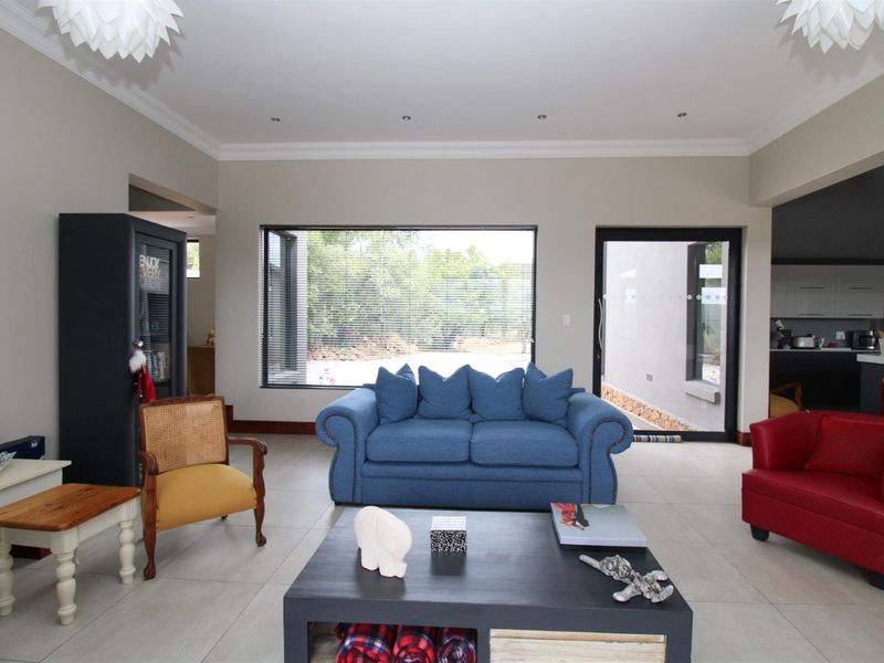 Spacious open-plan living area featuring large windows, tiled flooring, and recessed ceiling lighting, offering a bright and airy atmosphere.