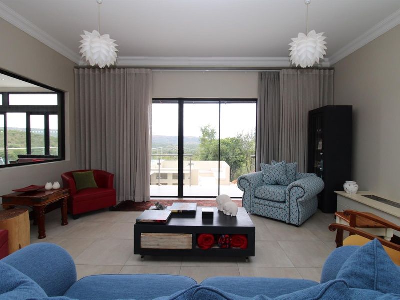 Spacious living room featuring large sliding glass doors that open to an outdoor patio, complemented by neutral floor tiles and elegant pendant lighting.