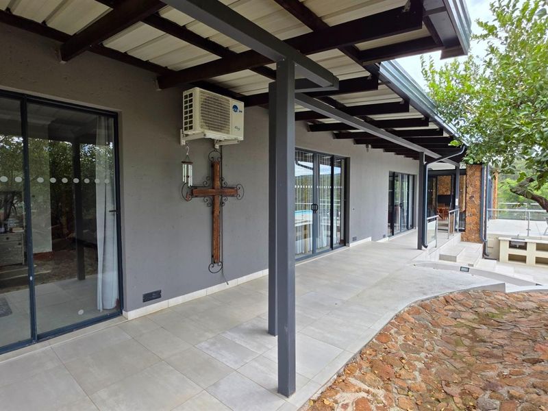 A covered patio area featuring tiled flooring, sliding glass doors, and an external air conditioning unit, providing a seamless transition to the outdoor space.