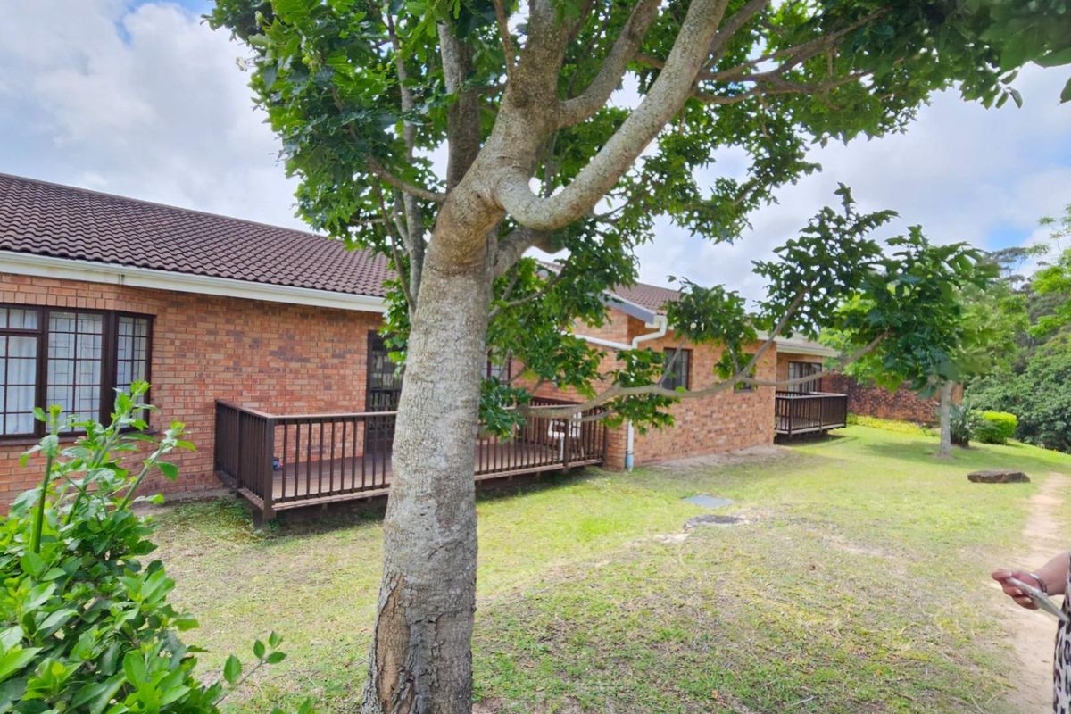 Rear view of the townhouse featuring face-brick exterior walls, tiled roof, and raised timber decks overlooking a shared garden area.