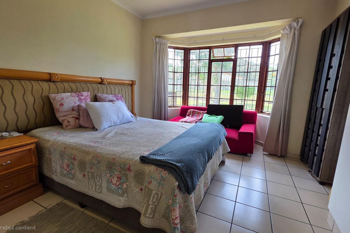 A bedroom featuring a large bay window with security bars, tiled flooring, and neutral wall finishes.