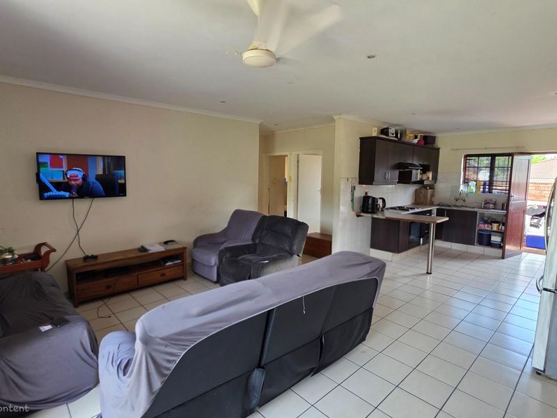 Open-plan living area featuring a kitchen with dark cabinetry and tiled flooring, seamlessly flowing into the lounge space.