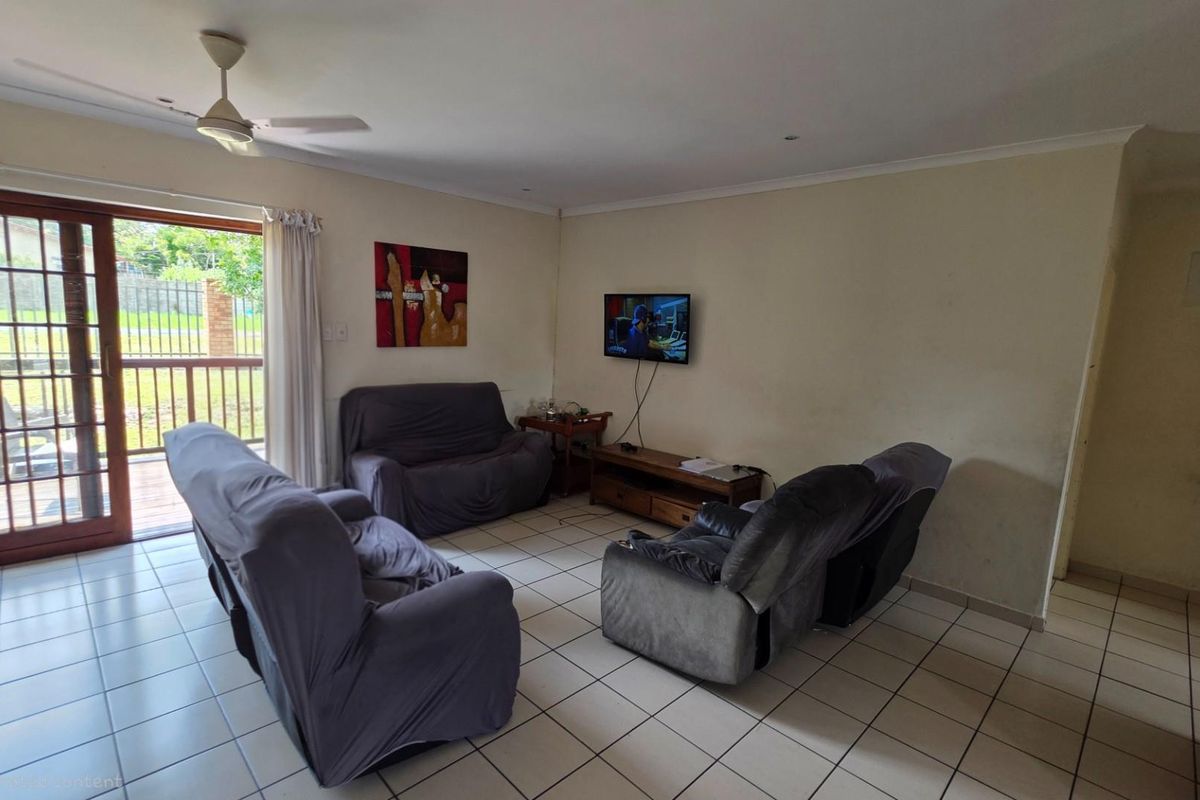 A living room featuring tiled flooring, a ceiling fan, and sliding glass doors providing access to an outdoor patio area.