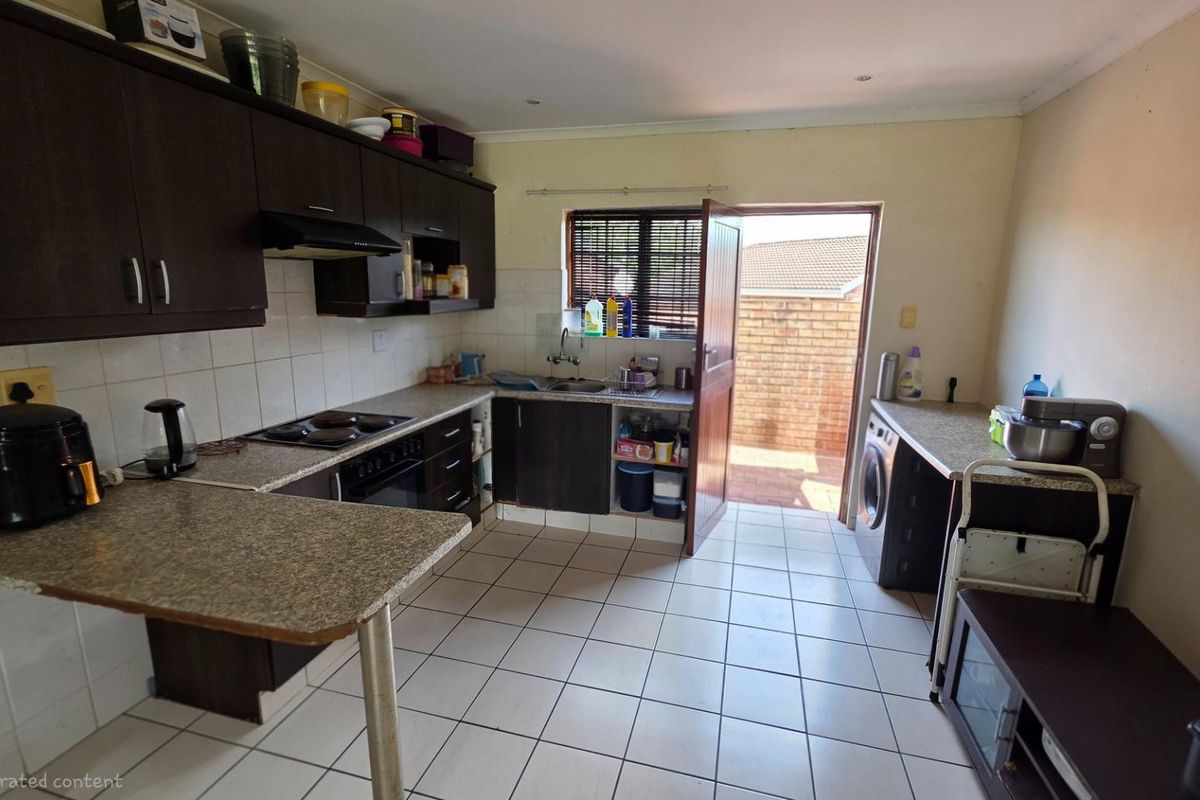 Functional kitchen featuring dark cabinetry, built-in oven and hob, tiled flooring, and direct access to an exterior courtyard area.