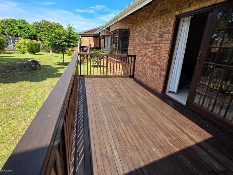 A wooden deck patio area featuring a timber balustrade, providing direct access to the garden and rear exterior of the townhouse.