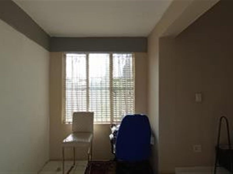 A simple bedroom space featuring a large window with fitted blinds, offering a neutral canvas for potential interior design updates.