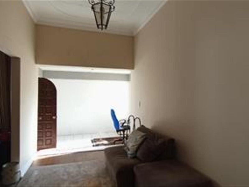 A living room area featuring coved ceilings, an ornate pendant light, and an arched doorway leading to an adjacent space.