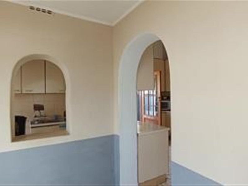 An open plan living area featuring a distinctive arched doorway and a serving hatch connecting to the kitchen space.