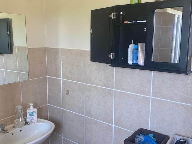 A functional bathroom featuring a pedestal basin and a wall-mounted medicine cabinet with tiled splashback finishes.