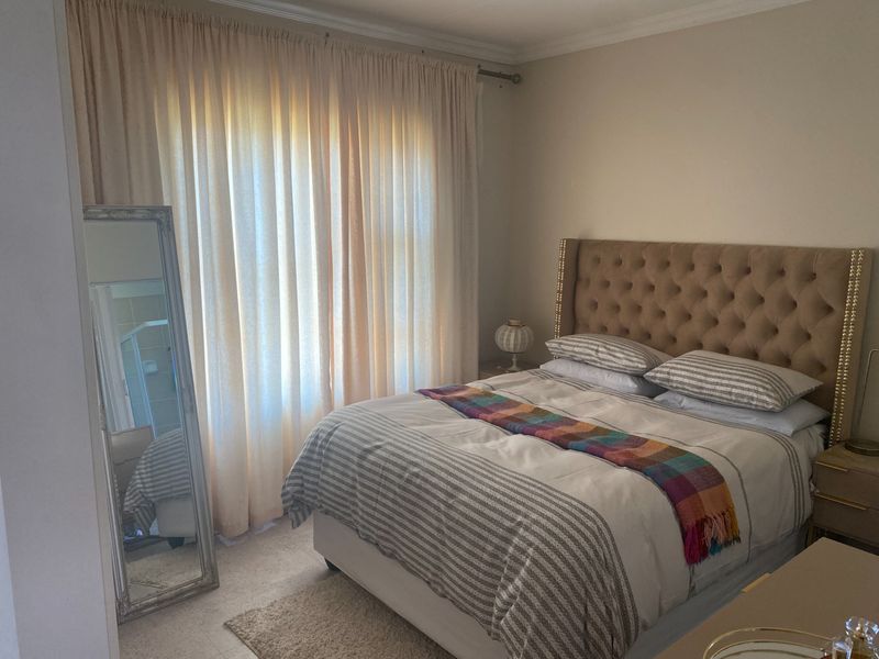 A well-lit bedroom featuring neutral wall tones, carpeted flooring, and decorative coving, providing a comfortable and functional living space.