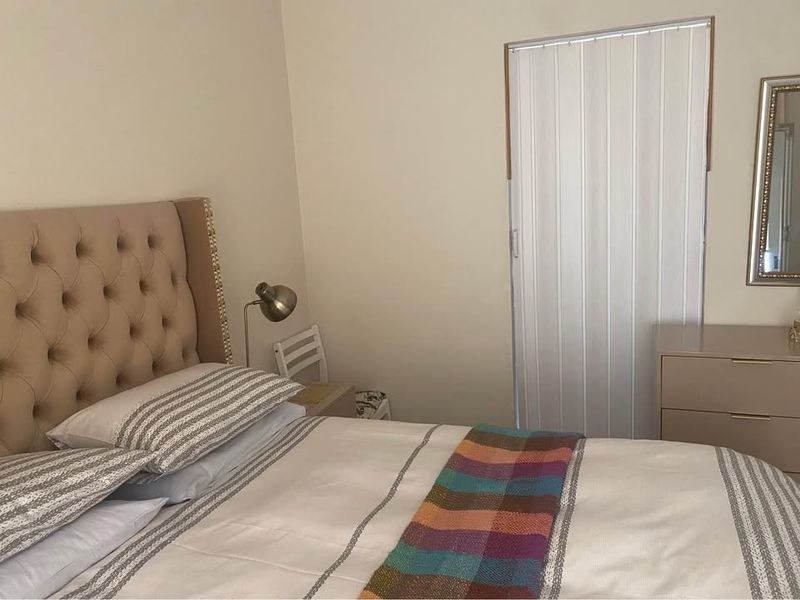 A bedroom featuring neutral wall finishes and a functional folding door, providing a simple and clean living space.