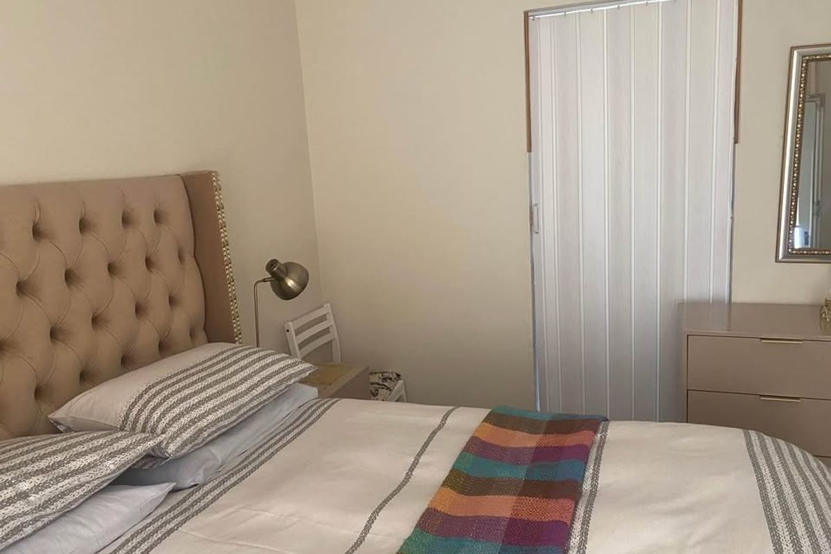 A bedroom featuring neutral wall finishes and a functional folding door, providing a simple and clean living space.