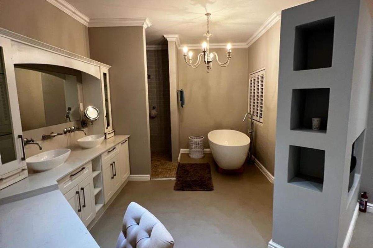 Spacious modern bathroom featuring a double vanity, freestanding bathtub, walk-in shower, and a unique built-in shelving partition with elegant lighting fixtures.