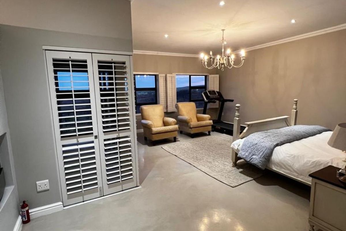 Spacious bedroom featuring polished concrete floors, recessed downlighting, and plantation shutters, offering a clean and modern aesthetic.