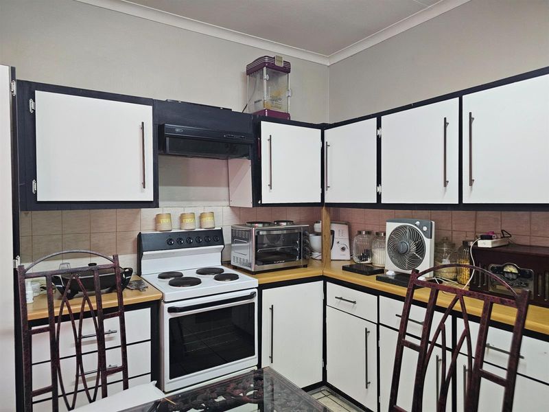 A functional kitchen featuring white and black cabinetry, laminate countertops, and a built-in electric stove with an extractor fan.