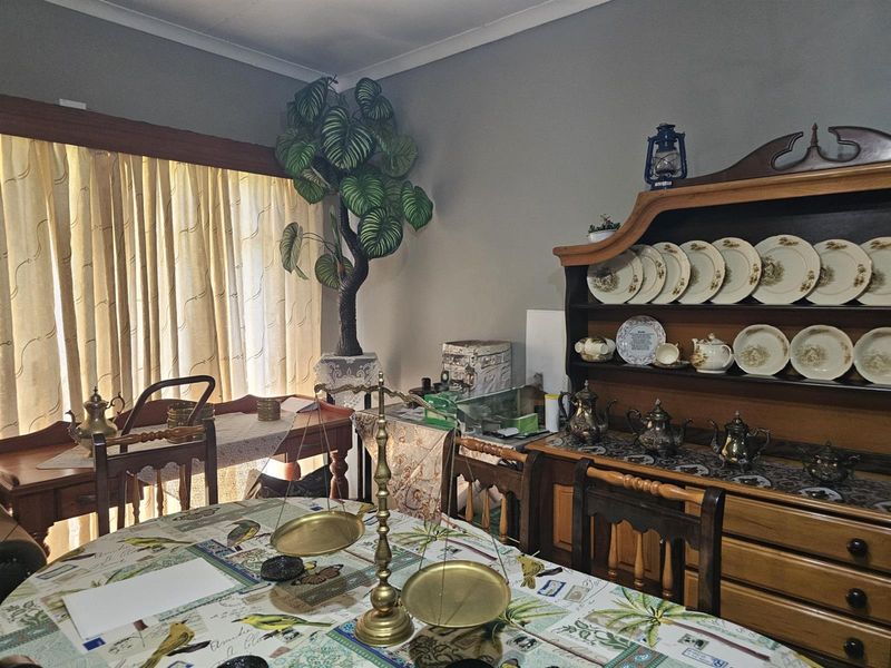 A dining room featuring neutral wall paint, coving, and large window with curtain rails, providing a functional space for family meals.