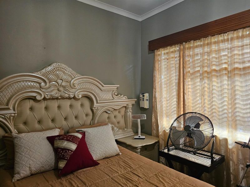 A bedroom featuring neutral wall paint, decorative coving, and a wooden curtain pelmet above the window.